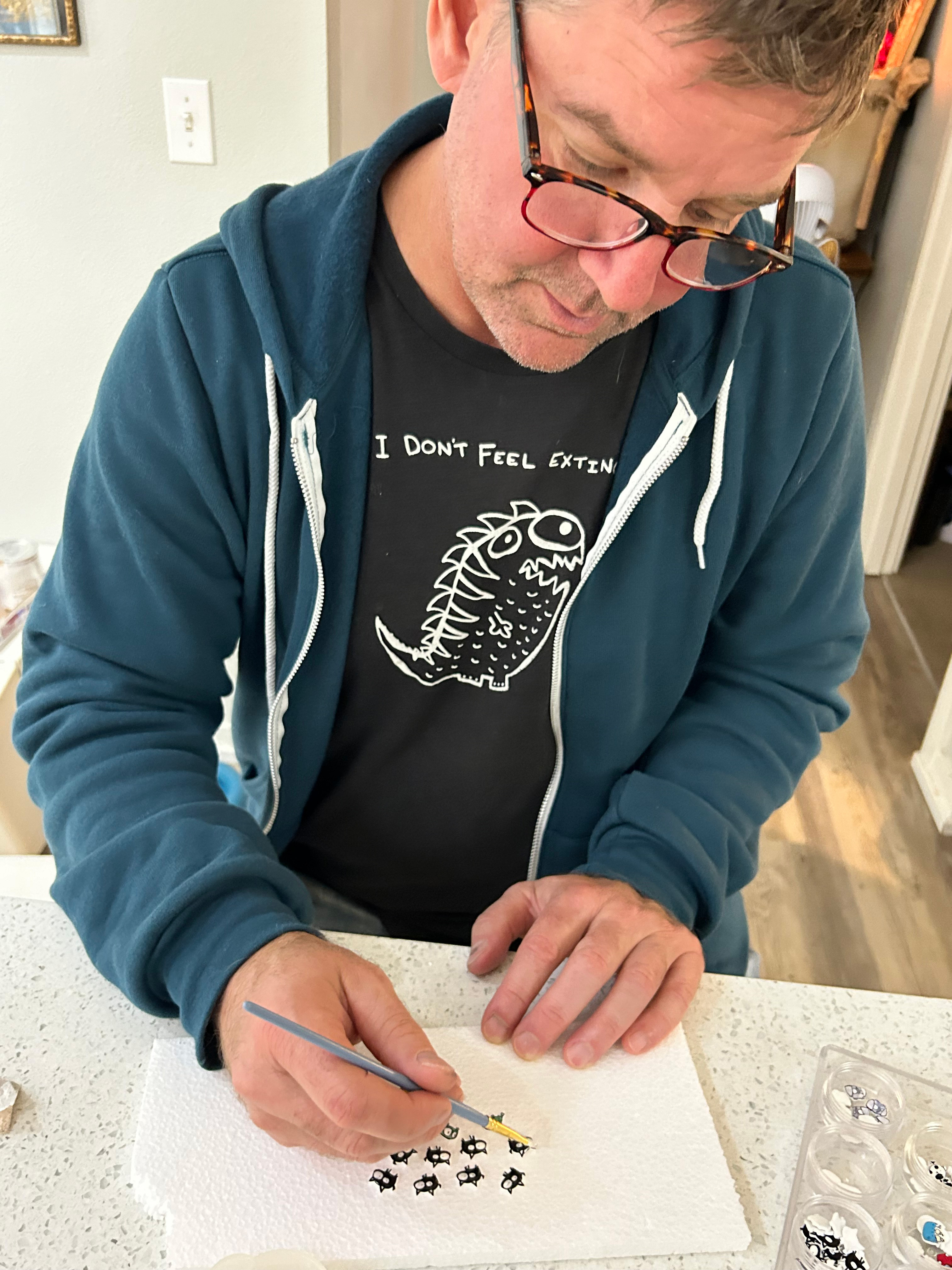 Artist Matt Wayne applying resin to monster earrings.
