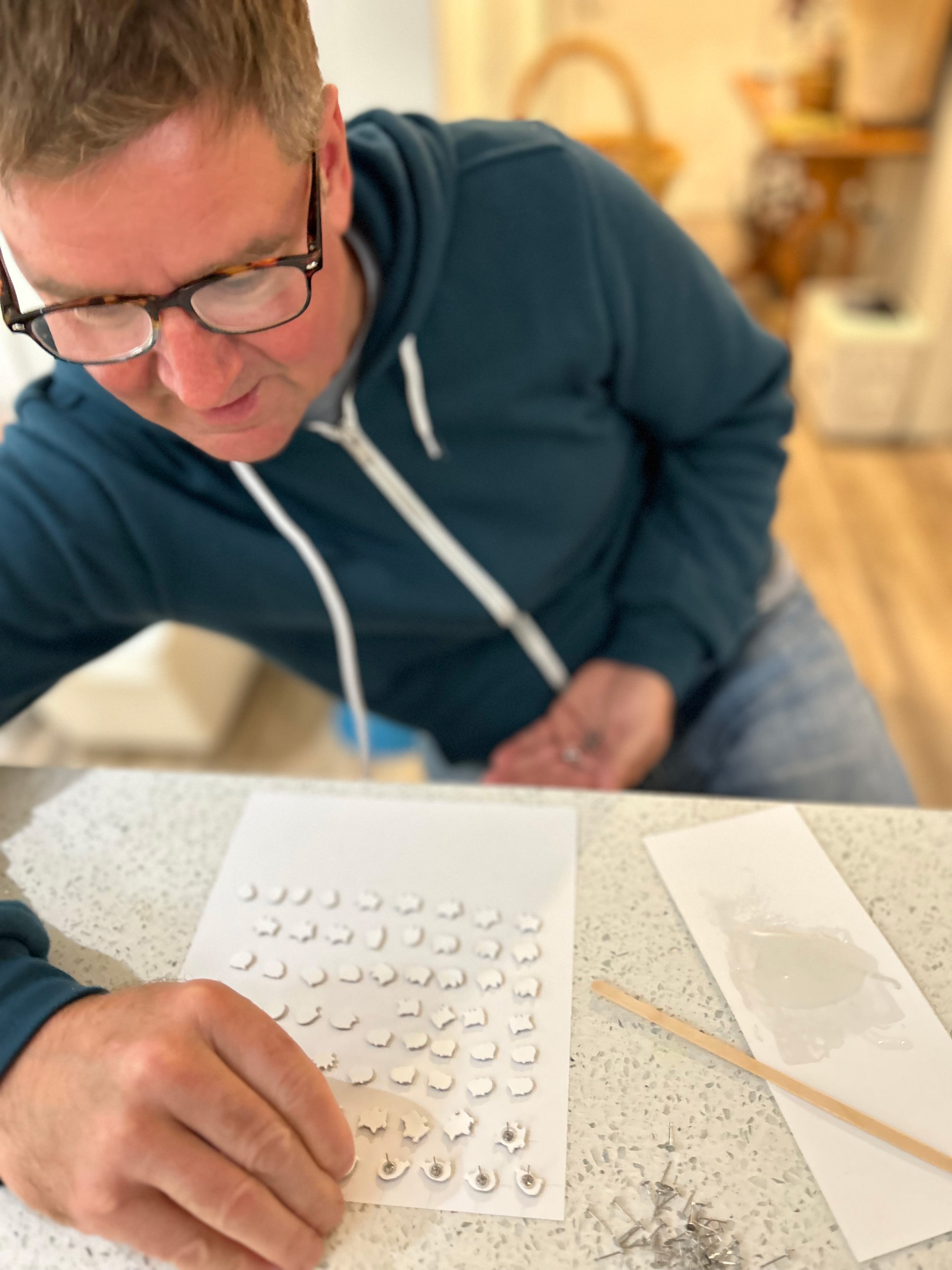 Artist Matt Wayne attaching posts to monster earrings.